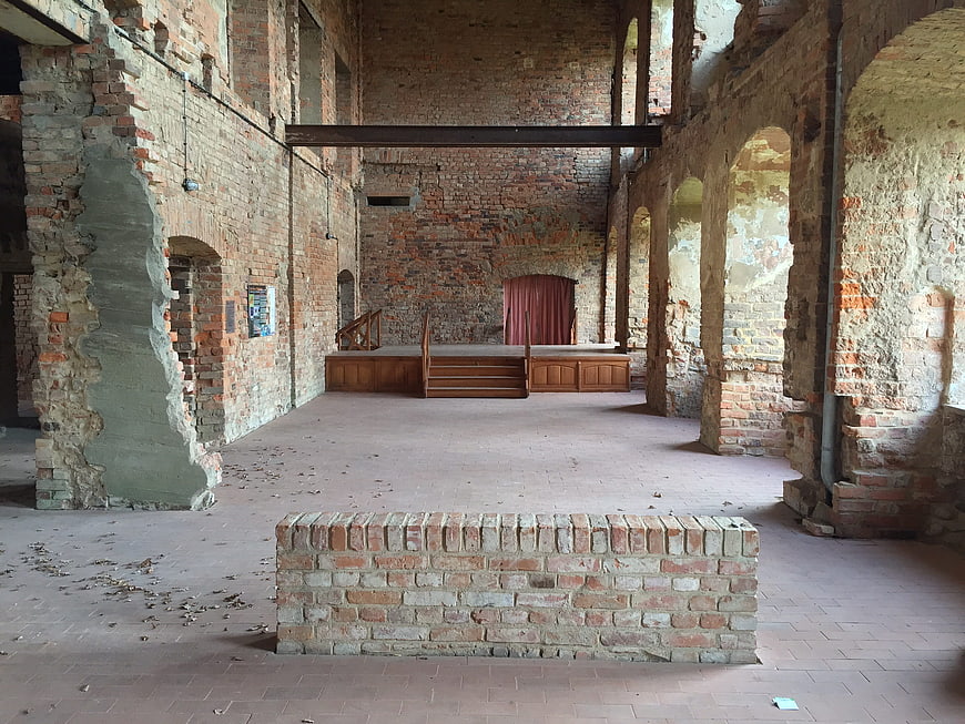 Abandoned brick hall with stage and red curtain