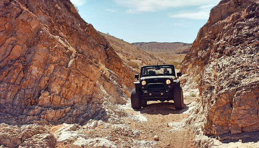 Black Jeep Wrangler Off-Roading Through Rocky Desert Canyon