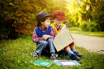 Two vintage-styled boys reading a book in a park