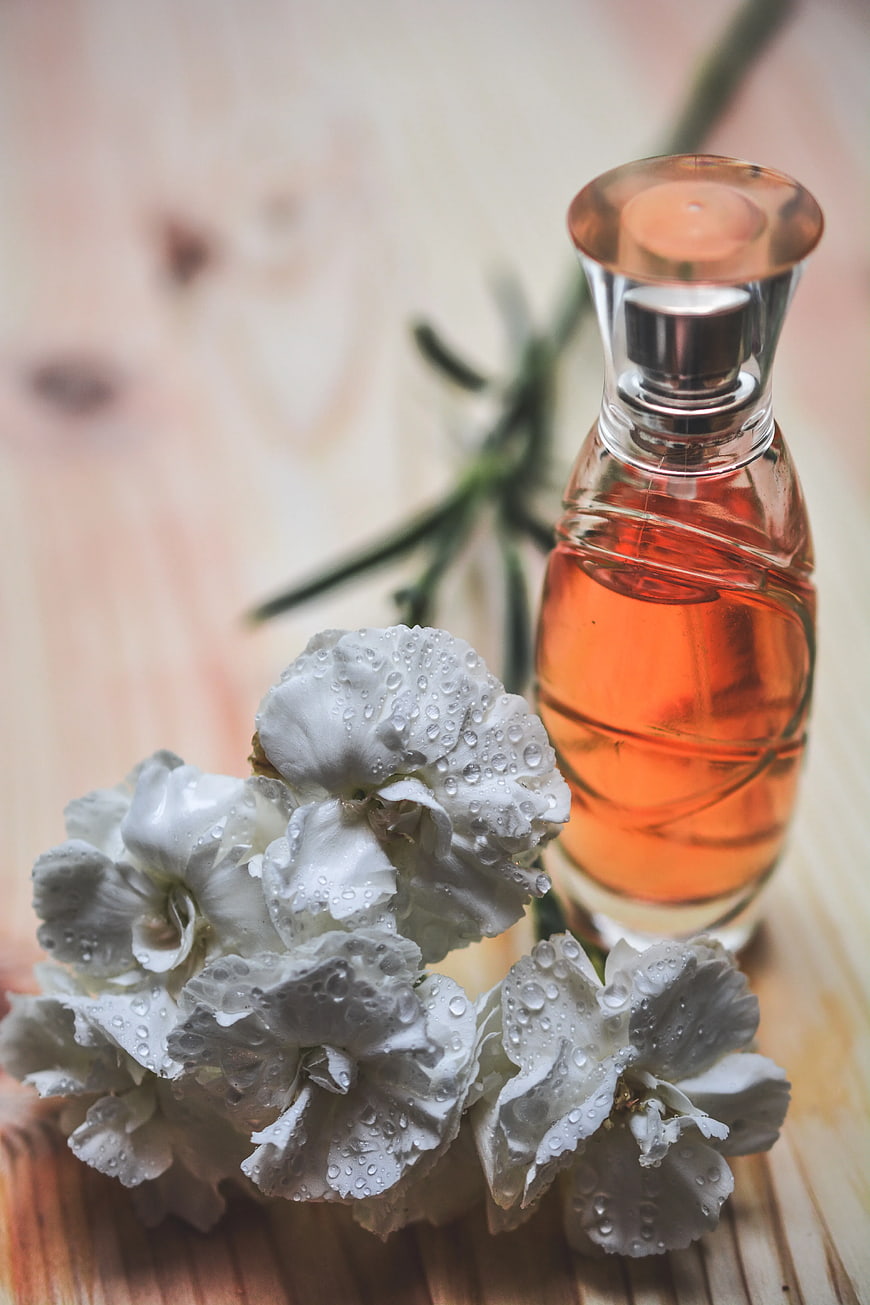 Perfume Bottle with White Carnations on Wood