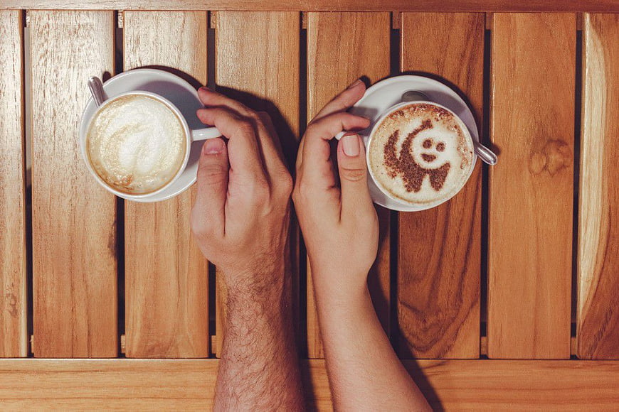 Top View of Couple Holding Cappuccino Cups on Wooden Table