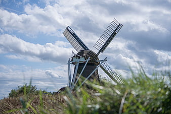 Traditional Dutch Windmill in Green Field with Cloudy Sky