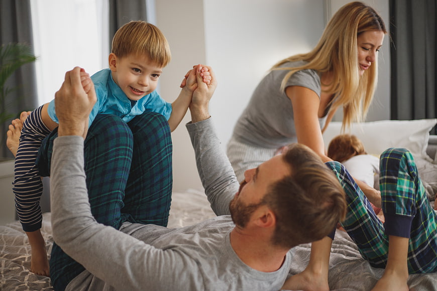 Happy family playing together on bed in pajamas