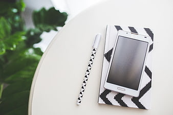 White smartphone on patterned notebook with pen
