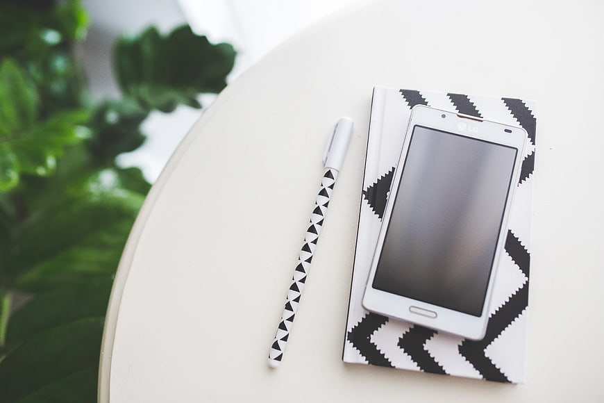 White smartphone on patterned notebook with pen