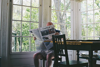 Senior Man Reading Newspaper in Sunlit Room