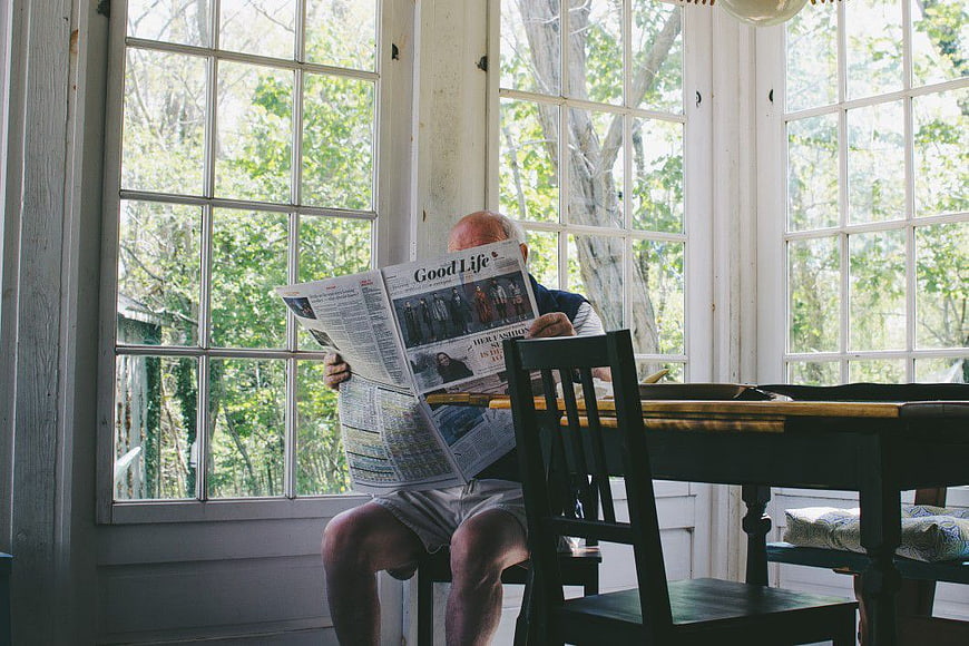 Senior Man Reading Newspaper in Sunlit Room