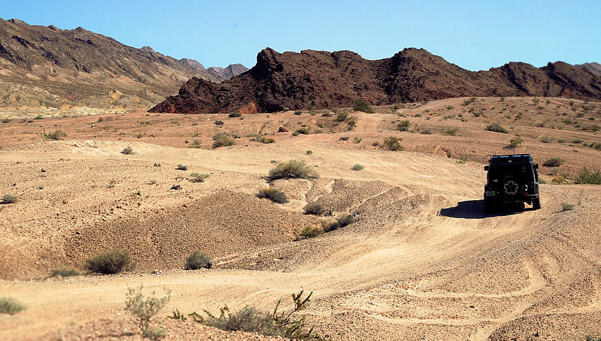 Black Jeep Driving on Desert Dirt Road with Mountains