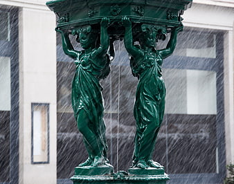 Green bronze caryatid fountain statues in heavy snowfall