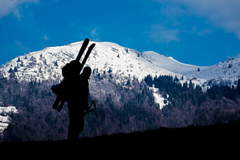 Silhouette of Skier with Skis Against Snowy Mountain
