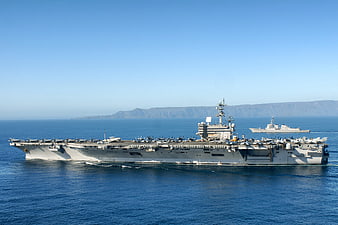 US Navy Aircraft Carrier Cruising Near Coastline
