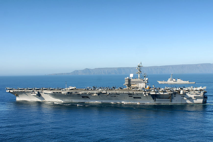 US Navy Aircraft Carrier Cruising Near Coastline