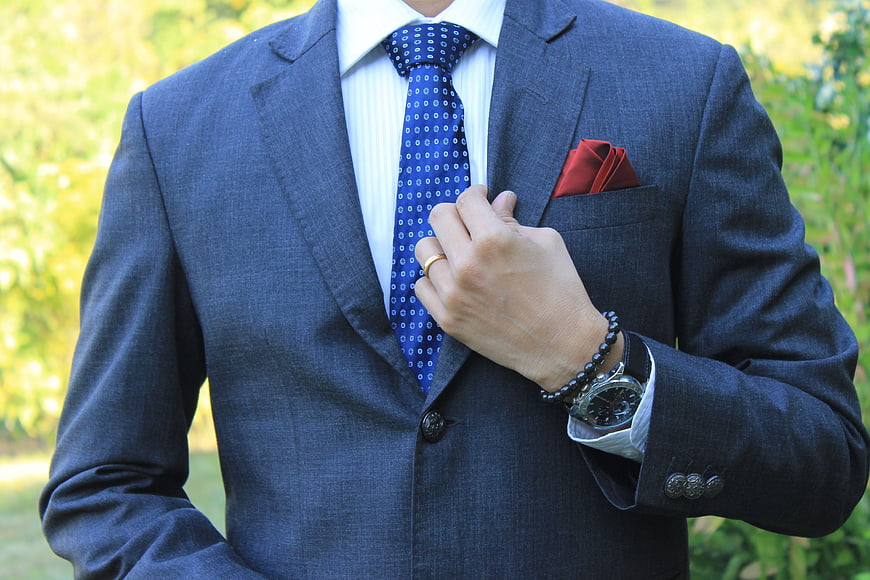 Professional man in blue suit adjusting tie outdoors