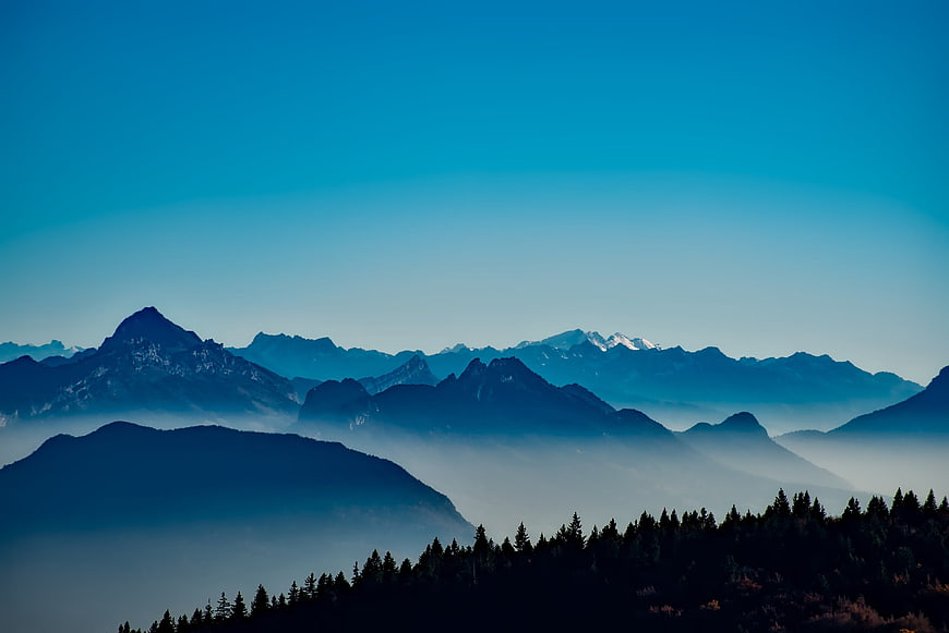 Blue mountain landscape with mist and forest silhouette