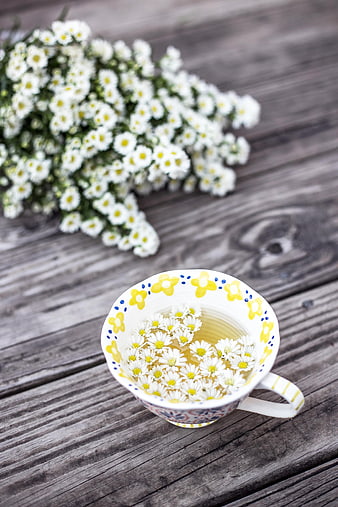 Chamomile Tea in Decorative Cup with Fresh Flowers on Wood