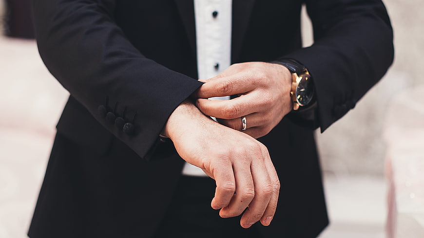 Man in Suit Adjusting Cufflinks with Gold Watch