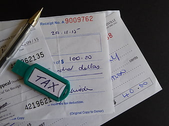 Charity Donation Receipts With Tax Tag And Pen On Dark Surface