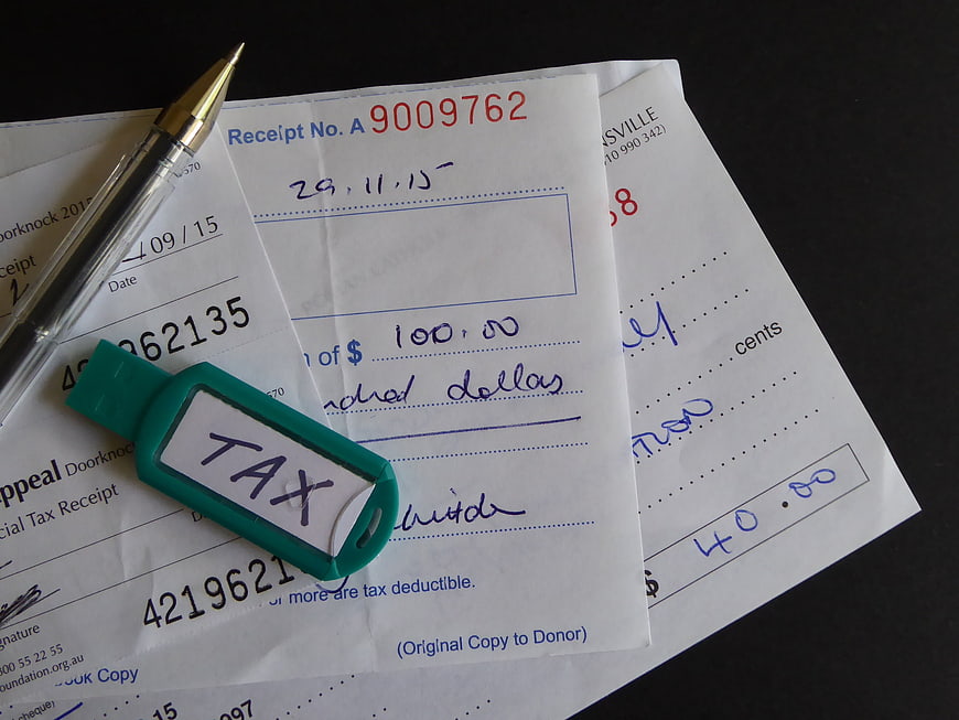 Charity Donation Receipts With Tax Tag And Pen On Dark Surface