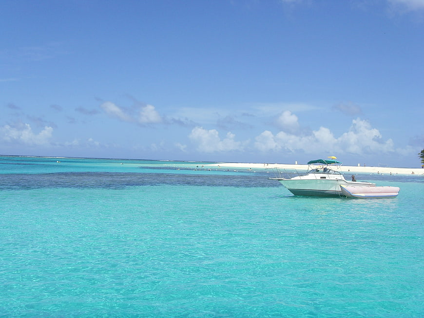 White boat anchored in turquoise tropical waters near white sandbar