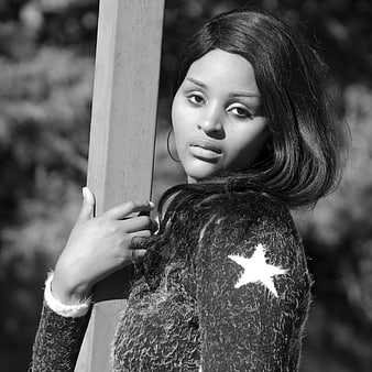 Black and white portrait of young African woman leaning on post