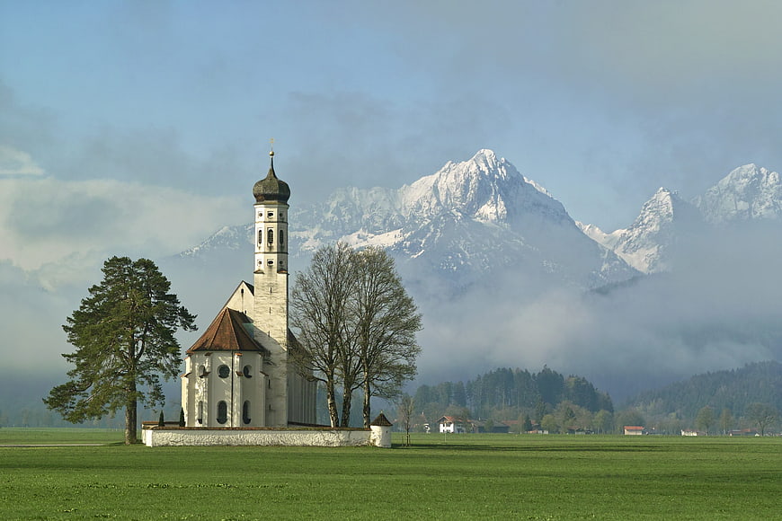 St. Coloman Church in Schwangau with Snow-Capped Alps and Misty Landscape