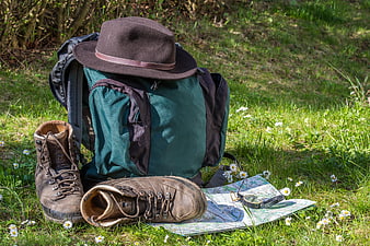 Hiking gear with backpack, boots, map, and compass on grass