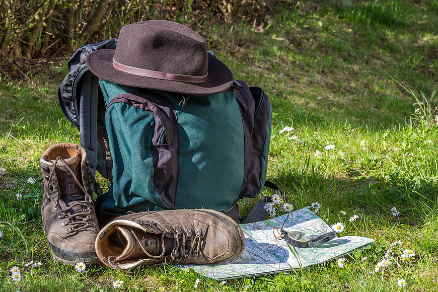 Hiking gear with backpack, boots, map, and compass on grass