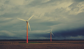 Wind turbines in a field under a dramatic cloudy sky