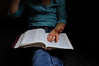 Child Reading Bible with Hand on Page