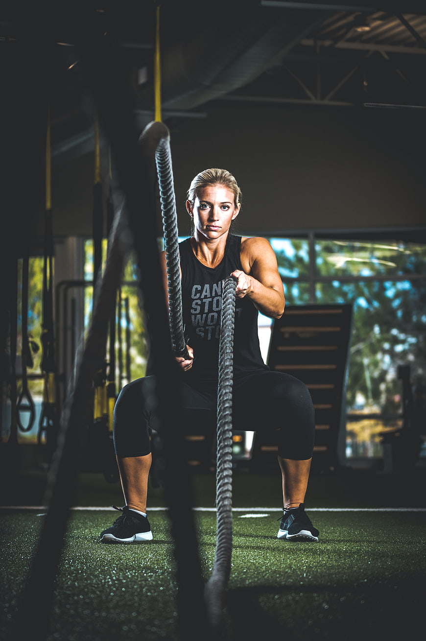 Athletic Woman Training with Battle Ropes in Gym