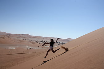 Woman jumping on sand dune in Namibian desert