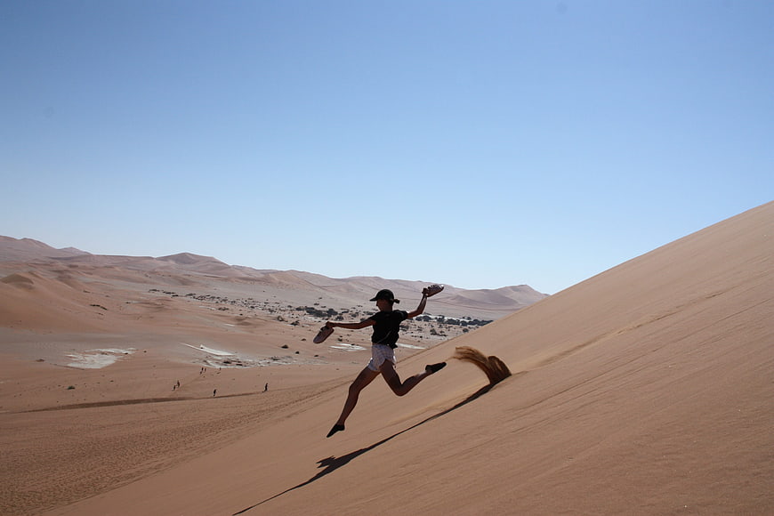 Woman jumping on sand dune in Namibian desert