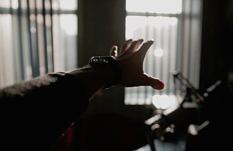 Silhouette of hand reaching toward window light