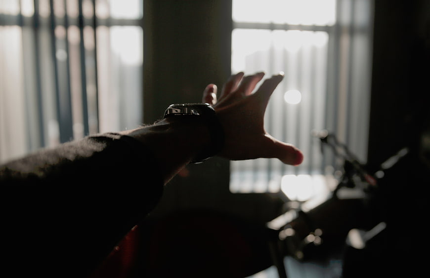 Silhouette of hand reaching toward window light