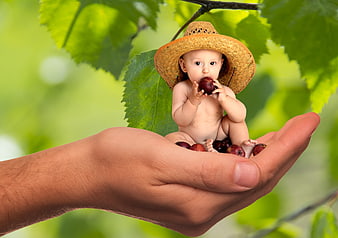 Cute baby in straw hat eating fruit in adult hand