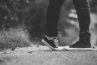 Black and white photo of person wearing high-top sneakers on gravel path