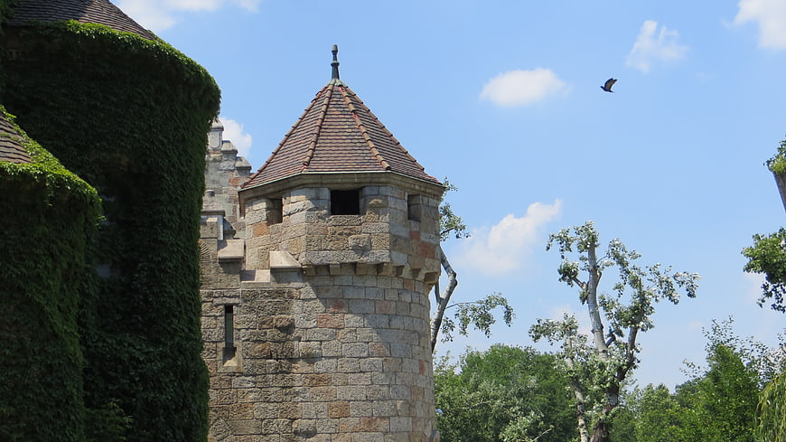 Medieval stone castle tower with ivy and bird in flight