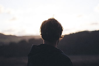 Silhouette of Man Looking at Sunset Over Hills