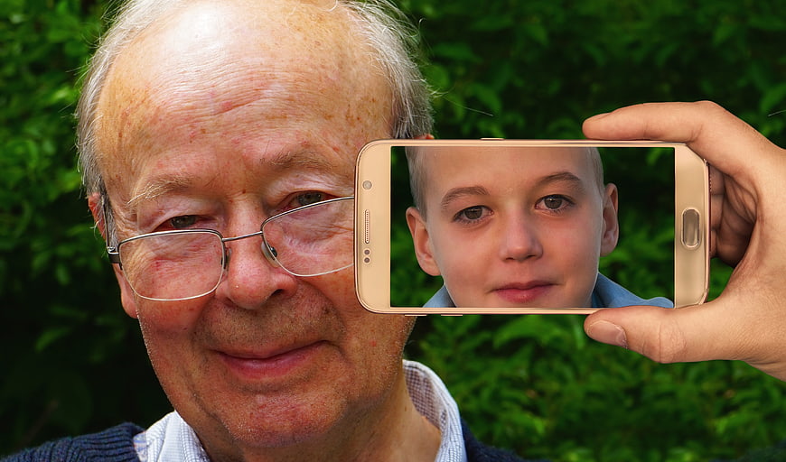 Senior man holding smartphone with child's face on screen