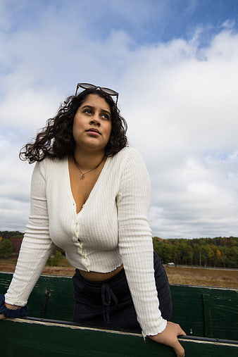 Young woman with curly hair leaning on green railing outdoors