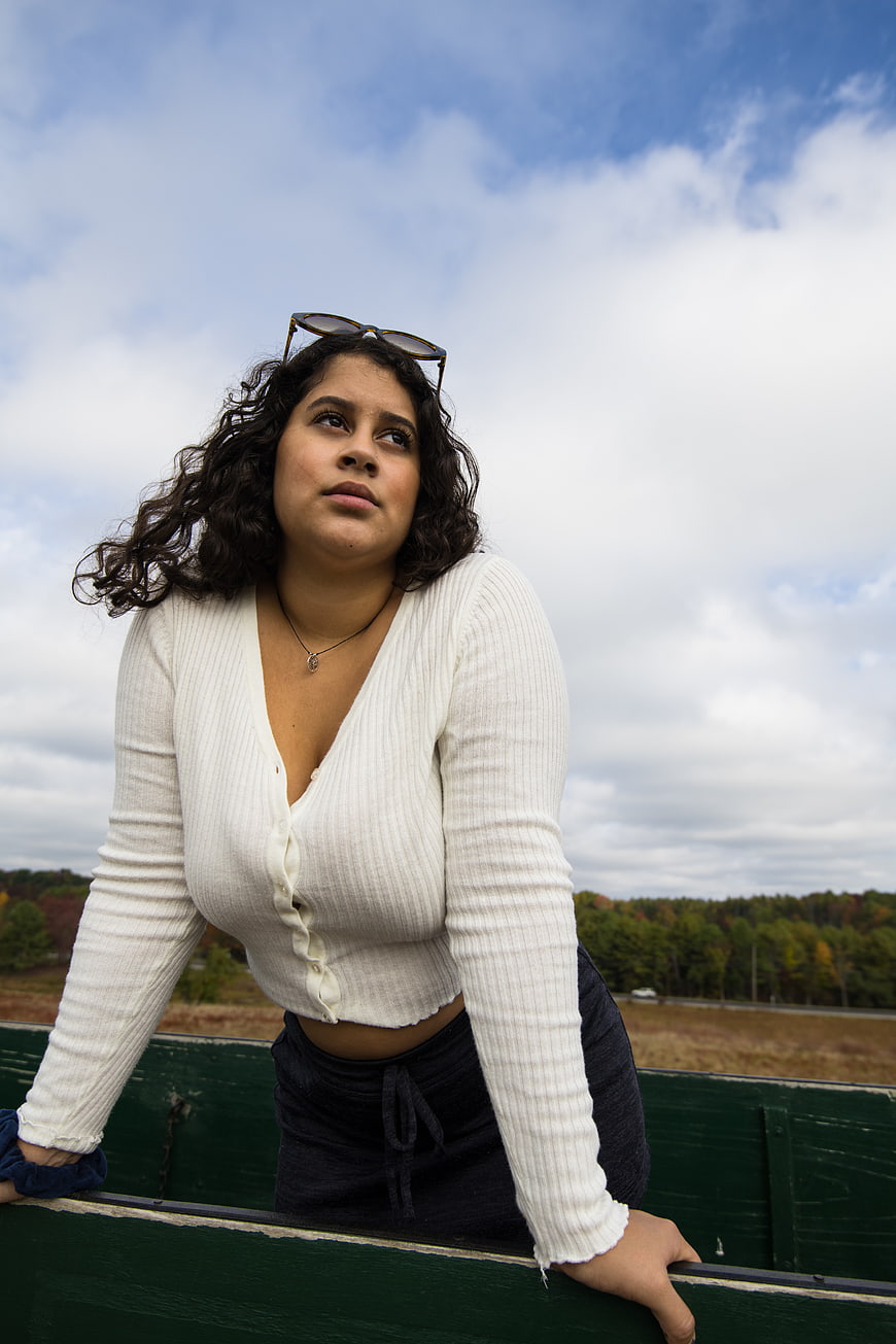 Young woman with curly hair leaning on green railing outdoors