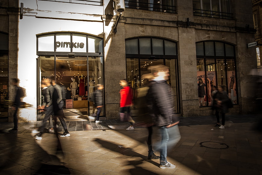 Motion blur pedestrians walking past Pimkie store
