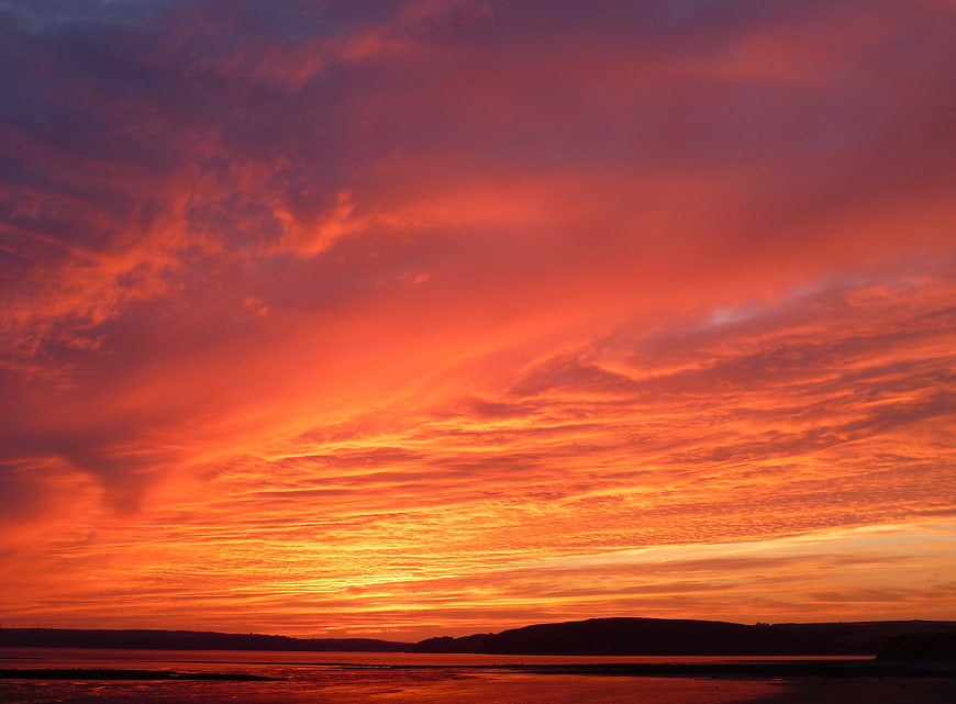 Vibrant orange sunset sky over calm ocean horizon