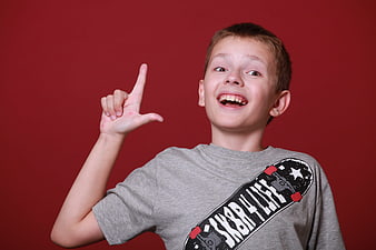 Happy Boy Pointing Up with Idea Gesture on Red Background