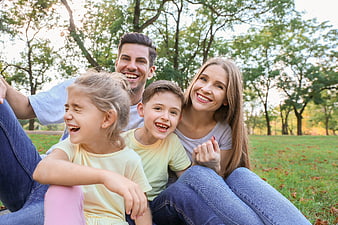 Happy family of four laughing together in a park