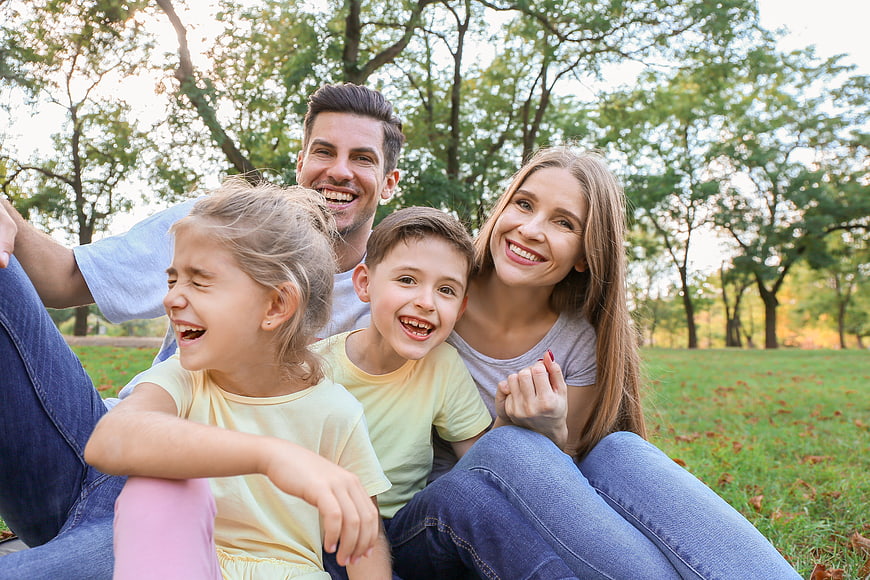 Happy family of four laughing together in a park