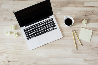Top view of laptop workspace with coffee and pencils on wooden desk