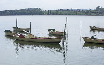 Rowboats moored on calm lake with green hills background