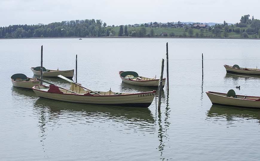 Rowboats moored on calm lake with green hills background