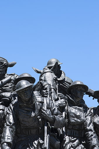 Bronze war memorial statue of soldiers and horses against blue sky